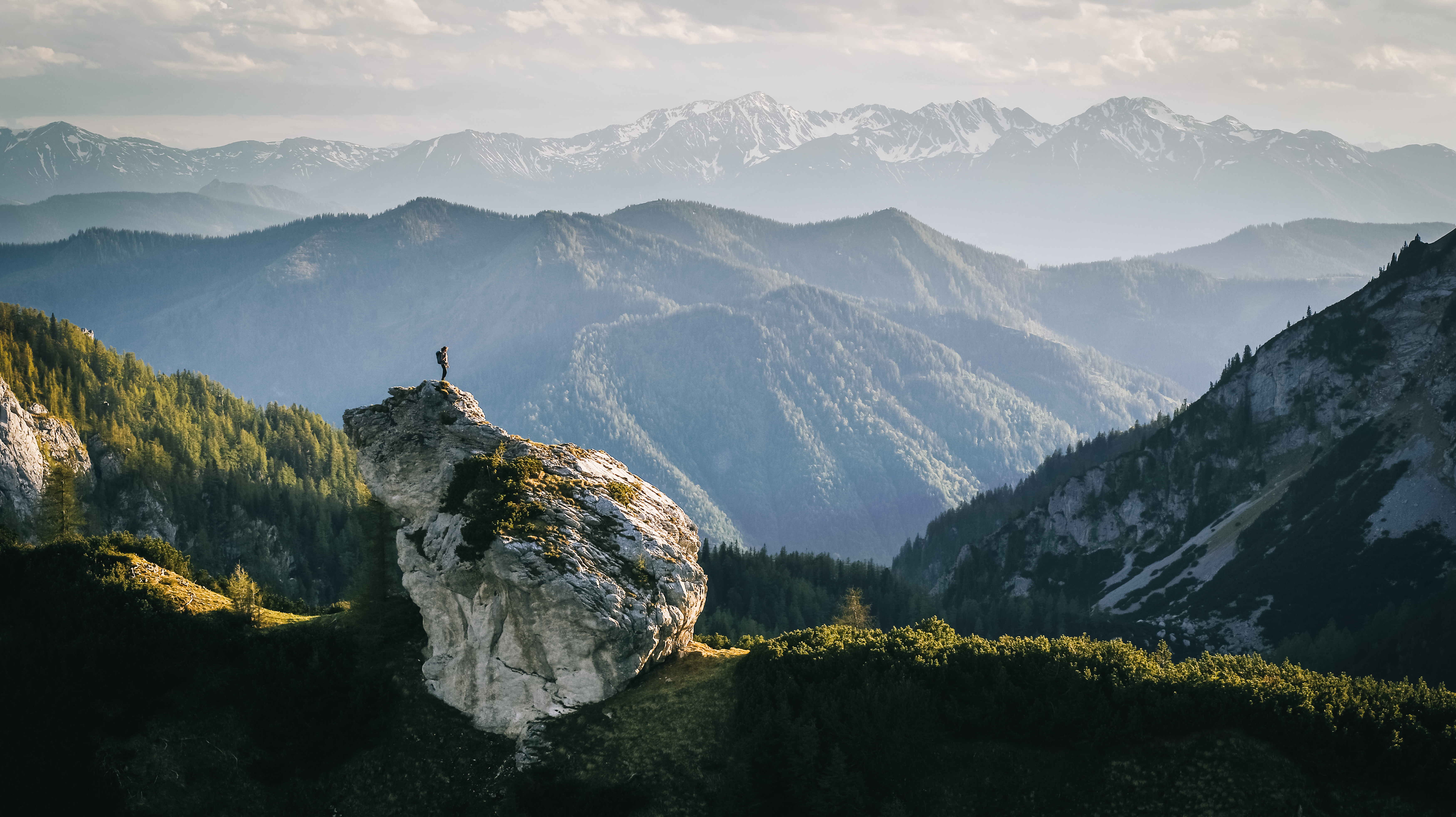 Wanderer auf einem Felsen mit Bergpanorama — Sinnbild für Perspektive und Entwicklung