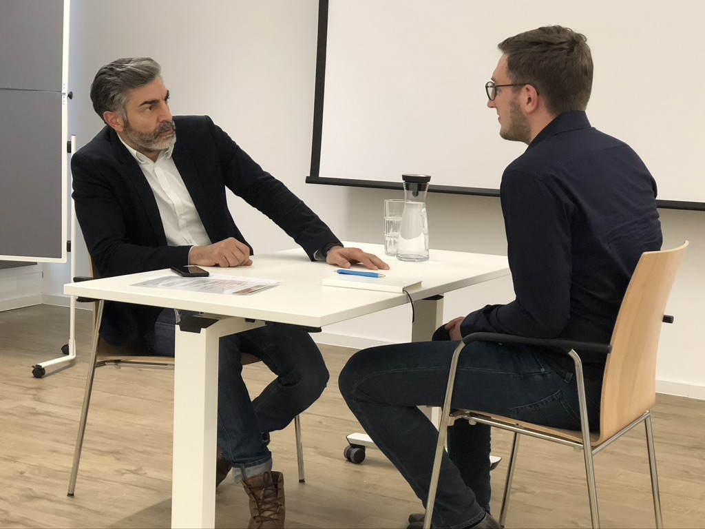 Trainingssituation mit Seminarschauspieler im Gespräch am Tisch