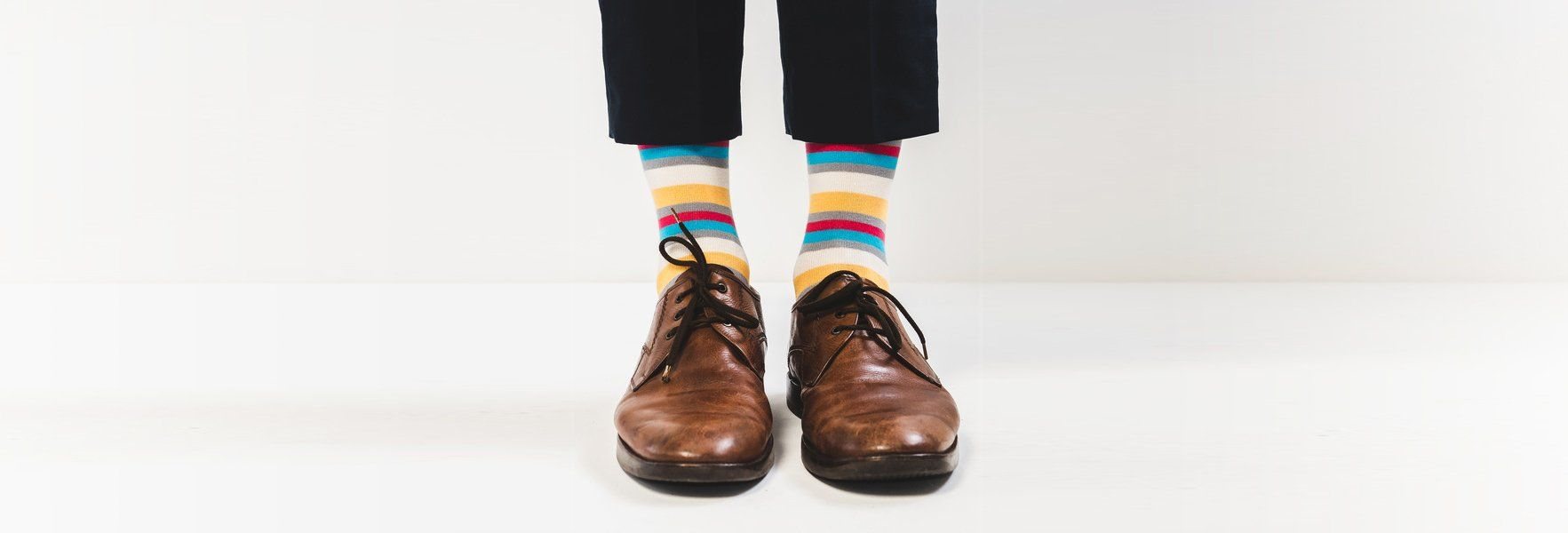 Braune Lederschuhe mit bunt gestreiften Socken — der erste Schritt
